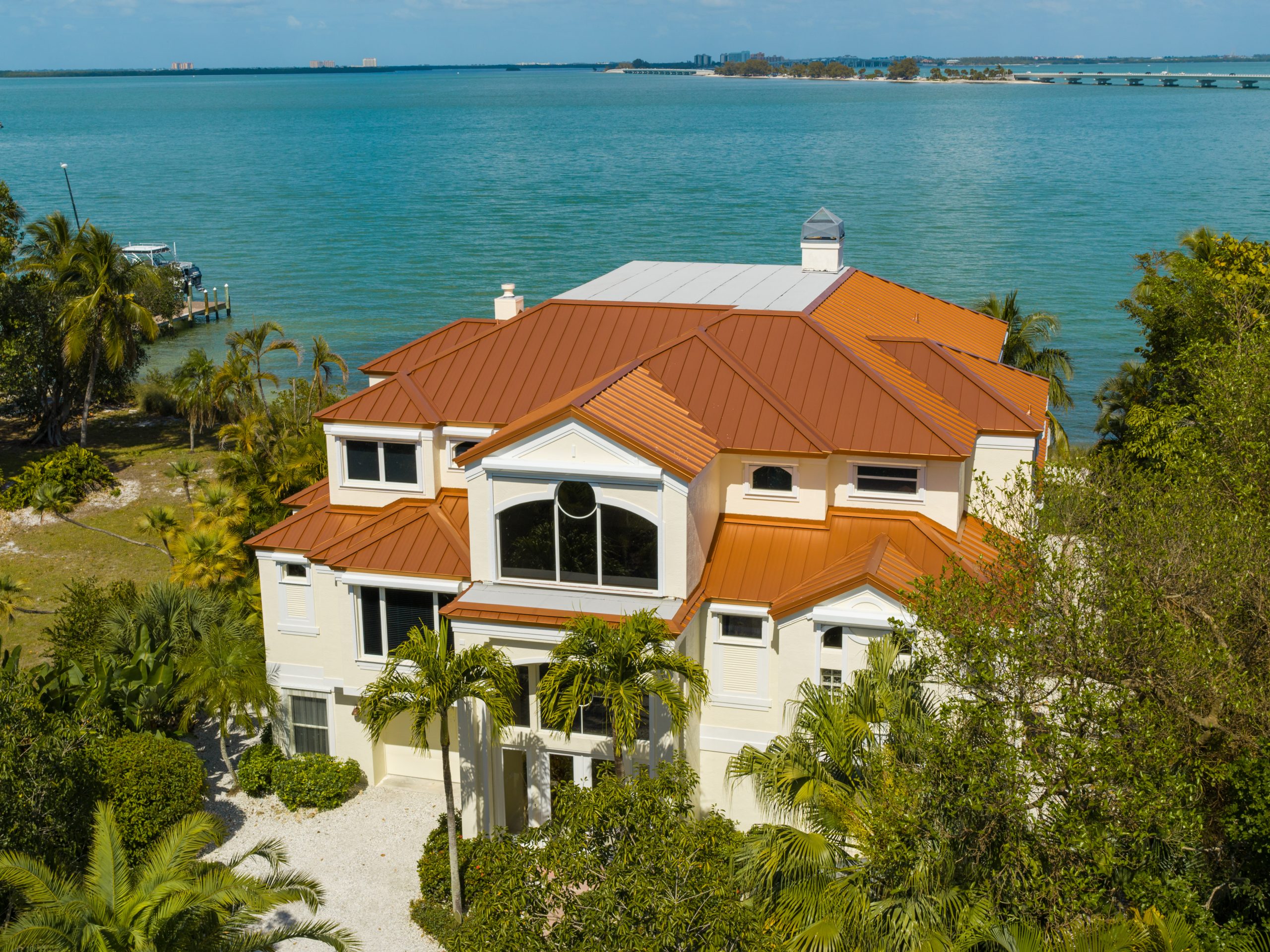 Beachfront house with red roof and palm trees.