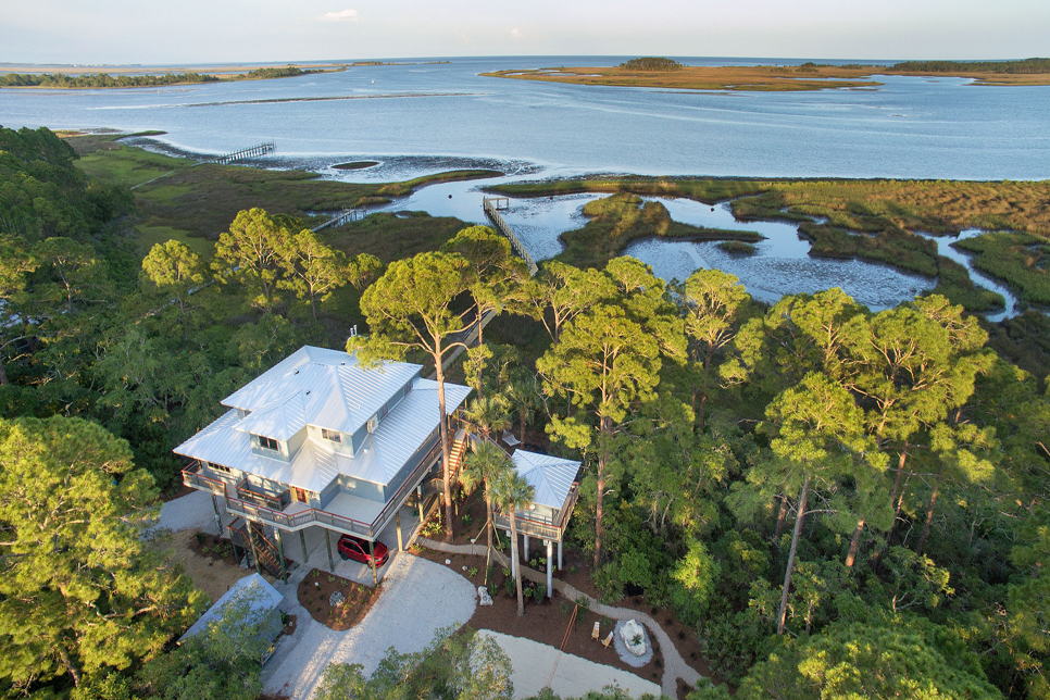Aerial view of coastal house and lush landscape.