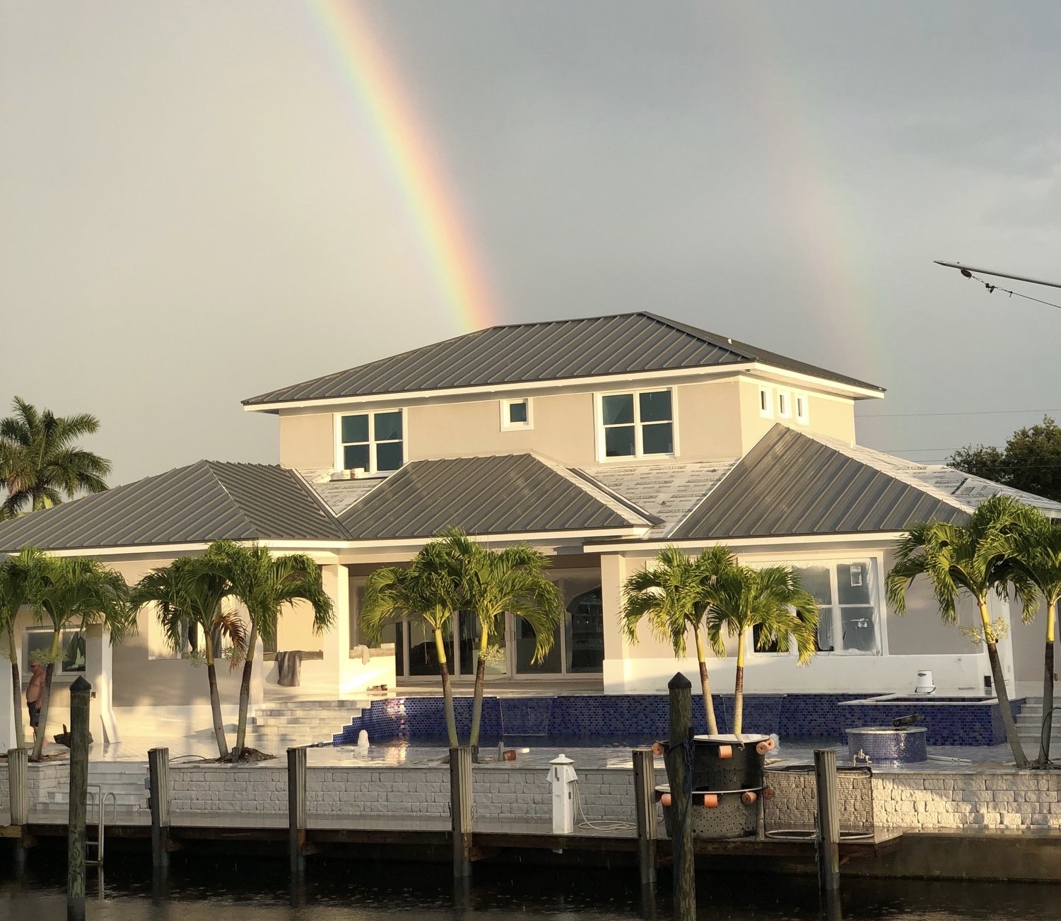 House by water with rainbow overhead.